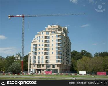 Construction crane and a new building. Blue sky background