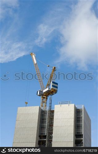Construction crane and building under construction against blue sky