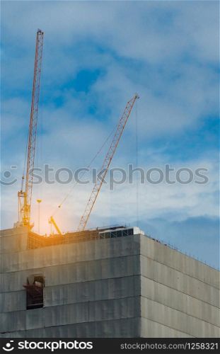 Construction crane on high-rise building with blue sky and white clouds. Construction site of commercial building or condominium or apartment in the city. Real estate business. Architecture background
