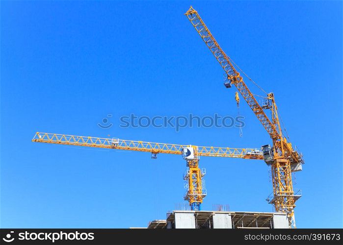 Construction cranes and the top of a skyscraper against the sky
