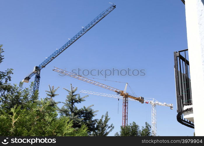 construction cranes silhouetted against a dark evening sky on a city centre building site.