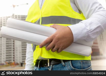 Construction engineer holding blueprints at building site