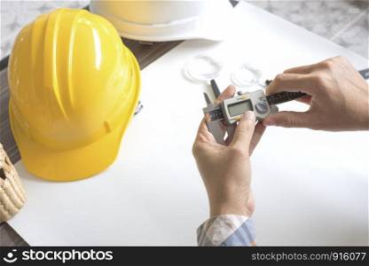 Construction engineer measuring with vernier caliper. Business and Technology concept. Safety helmet and Drawing paper elements. Civil and Drawing sketch theme.
