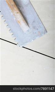 construction equipment dirty old trowel on new tile floor surface, tile floor adhesive