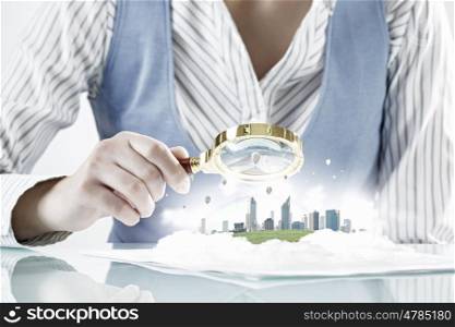 Construction expertise concept. Close view of businesswoman sitting at table and looking at project in magnifying glass