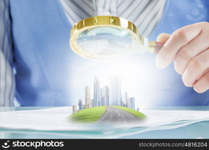 Construction expertise concept. Close view of businesswoman sitting at table and looking at project in magnifying glass