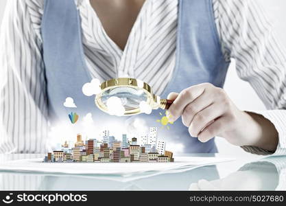 Construction expertise concept. Close view of businesswoman sitting at table and looking at project in magnifying glass