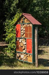 Construction for bird and insect hotel or home in garden with drilled tree trunks and branches. Bird and insect hotel made from tree trunks, bricks and other items