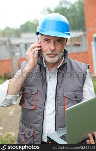 Construction manager on building site with laptop computer