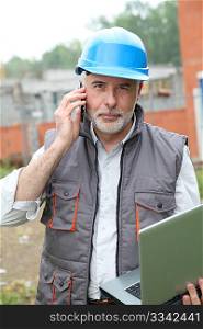 Construction manager on building site with laptop computer