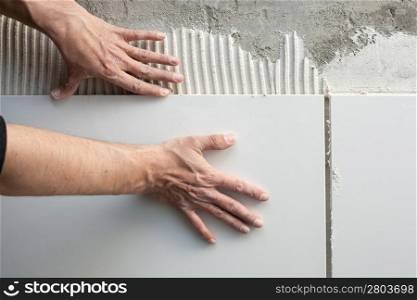 construction mason man hands on tiles work with notched trowel cement mortar