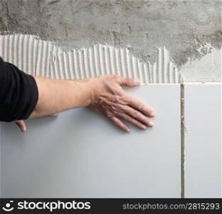 construction mason man hands on tiles work with notched trowel cement mortar