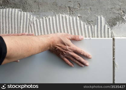 construction mason man hands on tiles work with notched trowel cement mortar