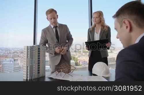 Construction presentation on office , two business people showing model of their project
