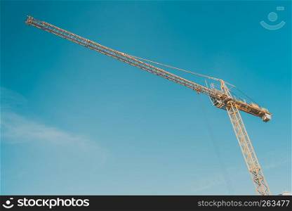Construction site building hoisting crane on evening clear blue sky background. Industrial object concept.. Crane against blue sky.