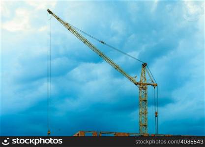 Construction site building hoisting crane on evening cloudy sky background