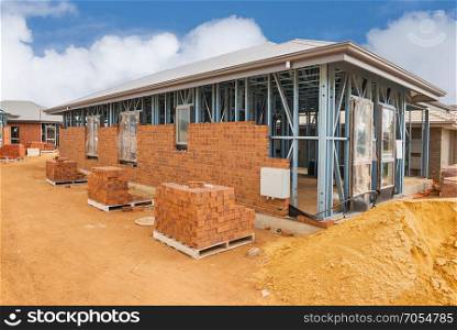 Construction site with homes from brick with metal framing against a blue sky.House construction site