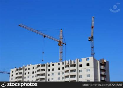 Construction site with two cranes against the sky