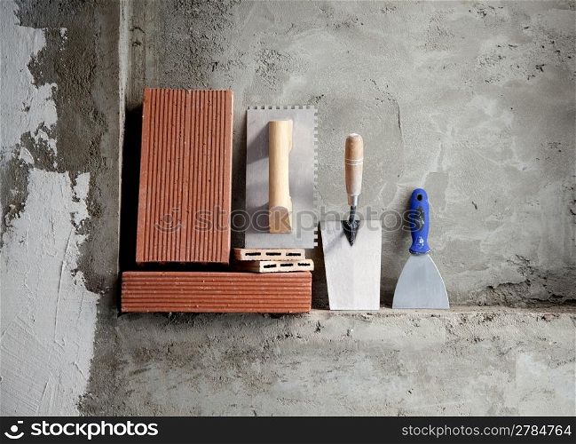 construction stainless steel trowel tools and bricks on cement mortar wall
