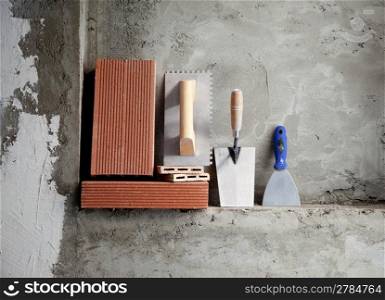 construction stainless steel trowel tools and bricks on cement mortar wall