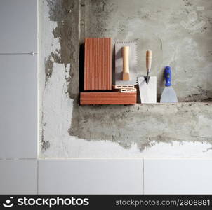 construction stainless steel trowel tools and bricks on cement mortar wall