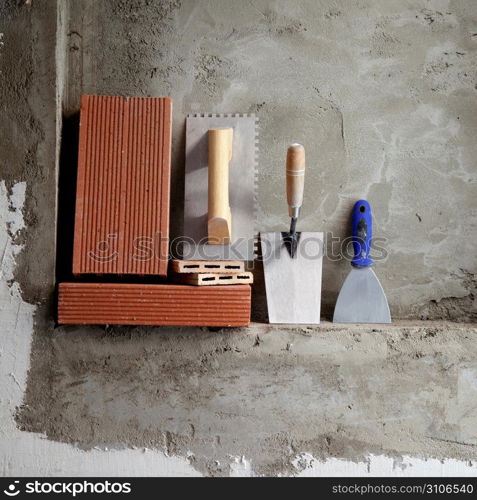 construction stainless steel trowel tools and bricks on cement mortar wall