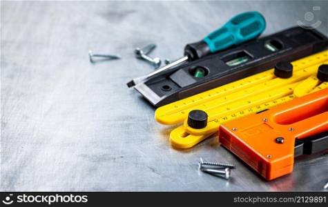 Construction stapler on the table. On a gray background. High quality photo. Construction stapler on the table.