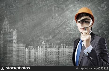 Construction strategy. Young man architect against sketch background looking in magnifying glass