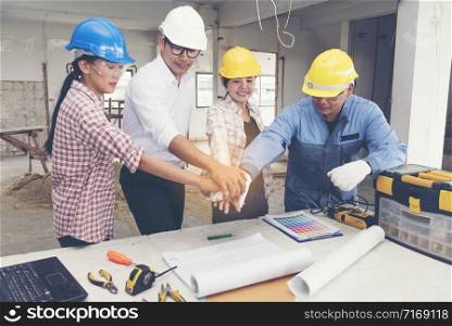 Construction teamwork shaking hands with engineer and foreman in construction site.