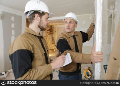 construction worker and apprentice talking notes