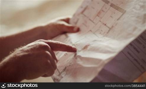 Construction worker and building plans, architect or engineer looking and examining blueprints of new houses and apartments. Rack focus from bricks to blueprint. Part 7 of 11