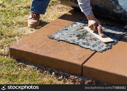 Construction Worker Applying Pressure to Texture Template On Wet Cement