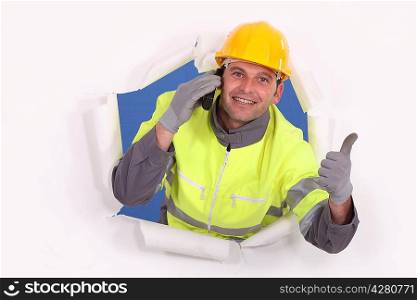 Construction worker breaking through a barrier and giving the thumb&acute;s up