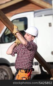 Construction worker carrying a heavy plank