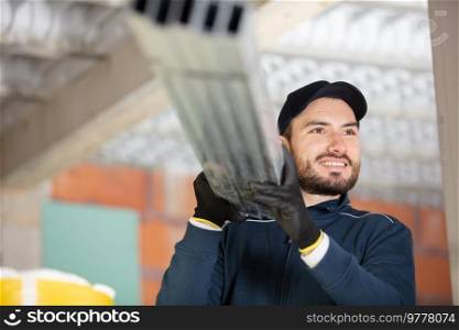 construction worker carrying reinforcement rods at building site