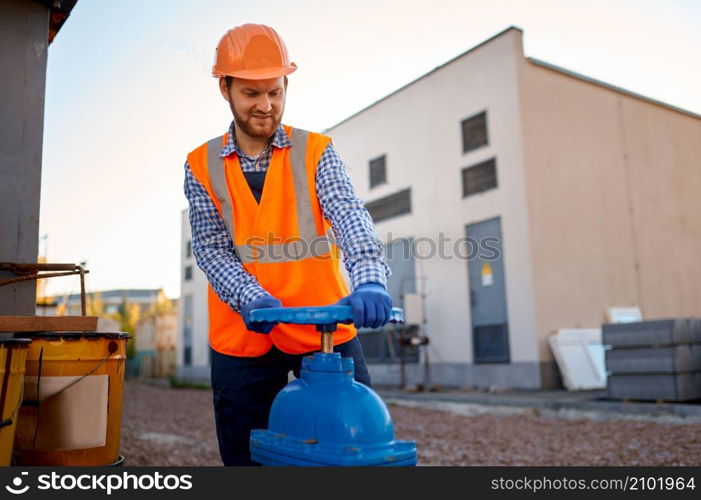 Construction worker checking industrial manufacturer gate valve and strainer at building site. Construction worker checking industrial manufacturer gate valve