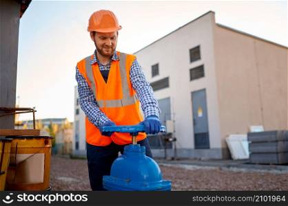 Construction worker checking industrial manufacturer gate valve and strainer at building site. Construction worker checking industrial manufacturer gate valve