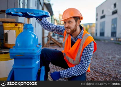 Construction worker checking industrial manufacturer gate valve and strainer at building site. Construction worker checking industrial manufacturer gate valve