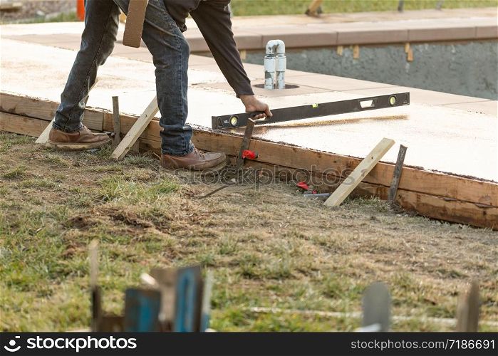 Construction Worker Checking Level On Wet Deck Cement