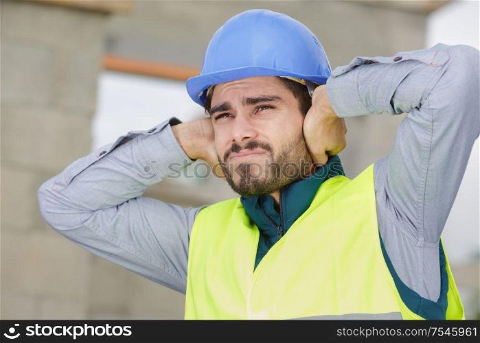 construction worker covering ears outdoors