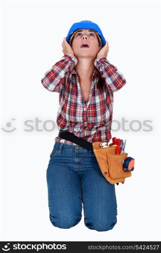 Construction worker covering her ears.
