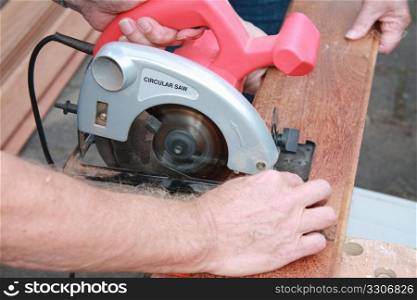 construction worker cutting wood with circular saw