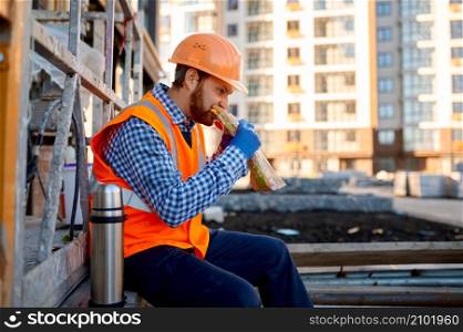 Construction worker eating sandwich during lunch. Take break and rest in middle of workday. Construction worker eating sandwich during lunch break