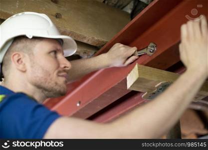 Construction Worker Fitting Steel Support Beam Into Renovated House Ceiling