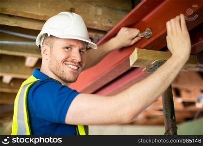 Construction Worker Fitting Steel Support Beam Into Renovated House Ceiling