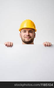 Construction worker holding a blank white board, on white background. Worker holding blank board on white background