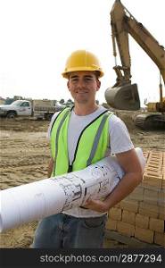 Construction worker holding blueprints on site, portrait