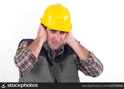 Construction worker holding his hands over his ears