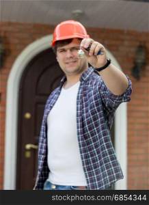 Construction worker holding keys from new house in hand
