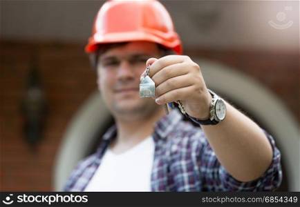 Construction worker holding keys from new house in hand